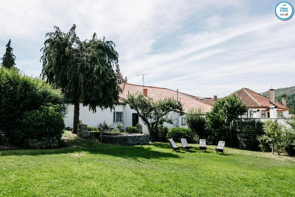 a yard with two chairs in front of a house at Casa da Tapa 7 in Vila Pouca de Aguiar