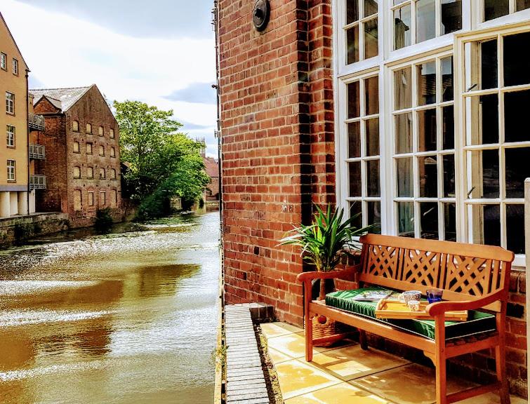 a bench sitting on a window sill next to a river at Cocoa Lily - River fronted studio with secure parking in York