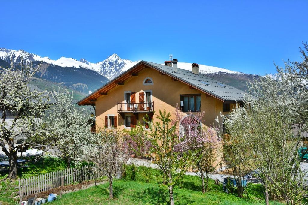a house with a balcony and mountains in the background at Gite-Auberge de Montvilliers in Aime
