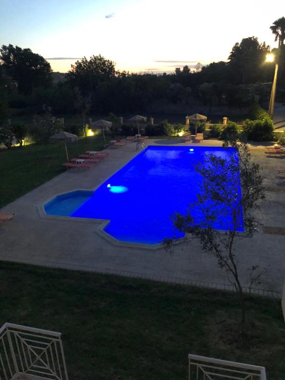 a large blue swimming pool at dusk at Mythos apts rentit in Agios Stefanos