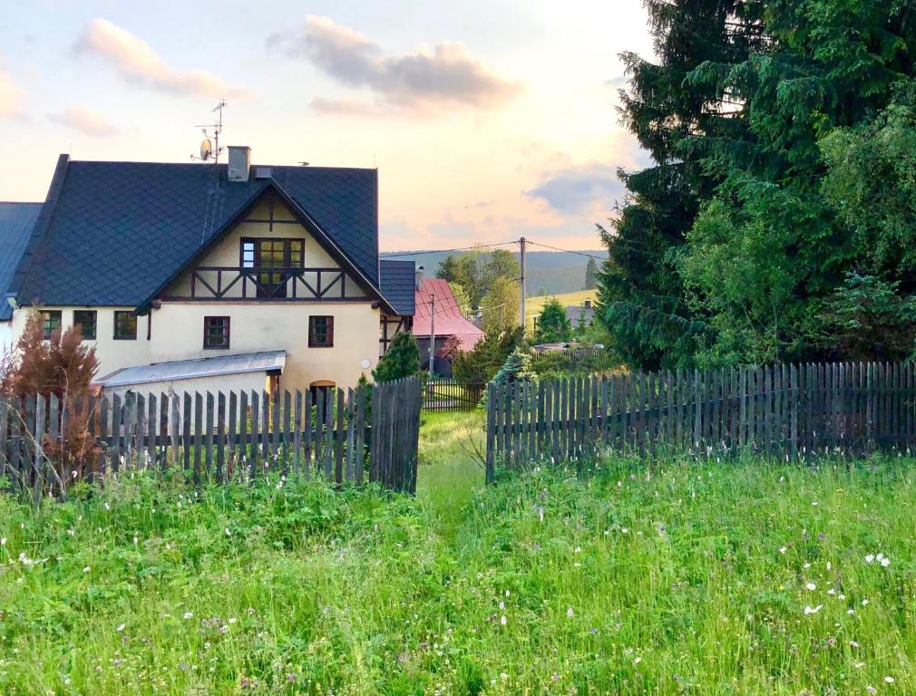 une maison blanche avec une clôture dans un champ dans l'établissement Chalupa Hrázděnka v Krušných horách, à Horní Blatná