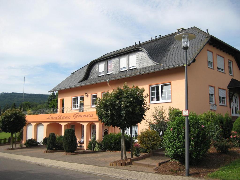 ein großes orangefarbenes Gebäude mit schwarzem Dach in der Unterkunft Landhaus Goeres in Briedel