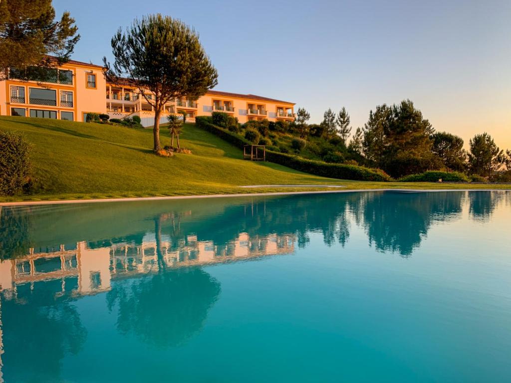a pool of blue water with a building in the background at Hotel Segredos De Vale Manso in Martinchel