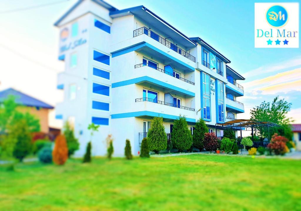 un edificio blanco con balcones azules en un patio en Vila Del Mar, en Costinesti