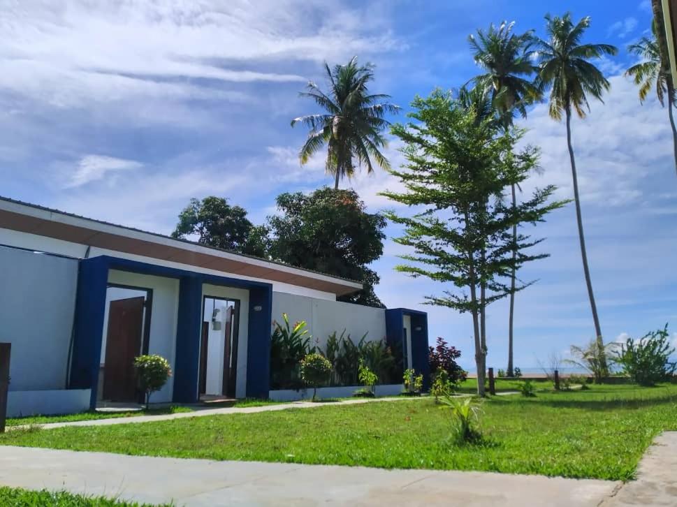 a house with palm trees in the background at Rafflesia Resort in Lundu