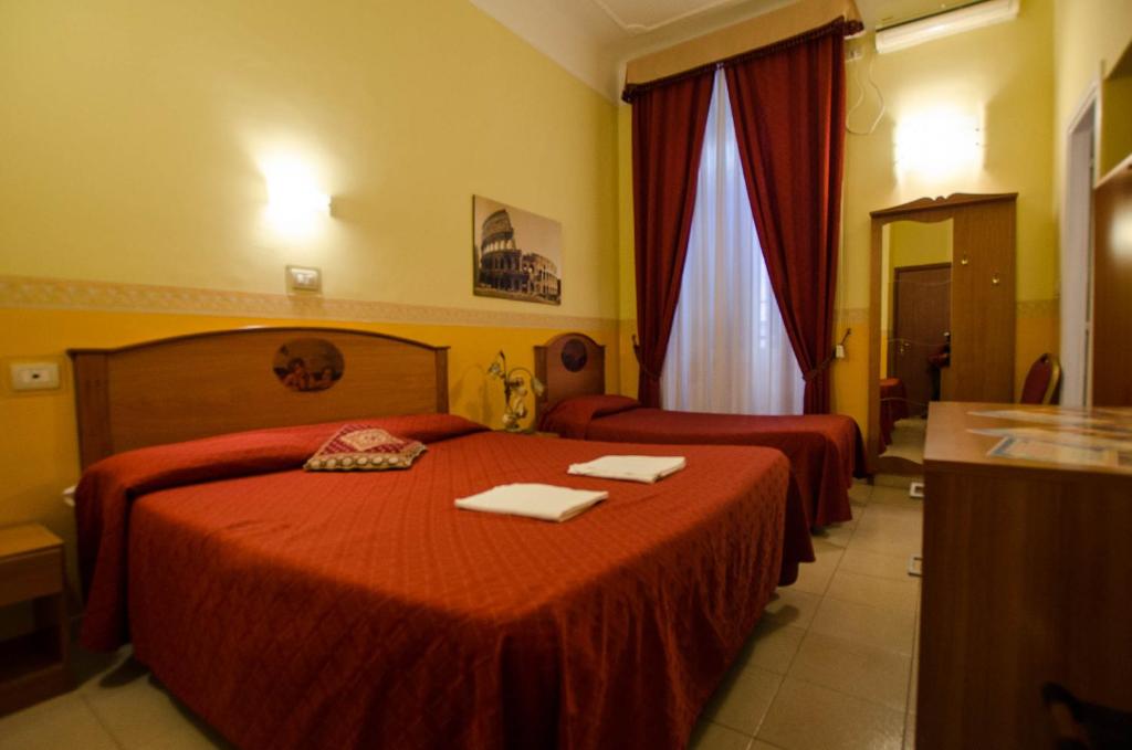 a hotel room with two beds and two tables at Hotel Cherubini in Rome