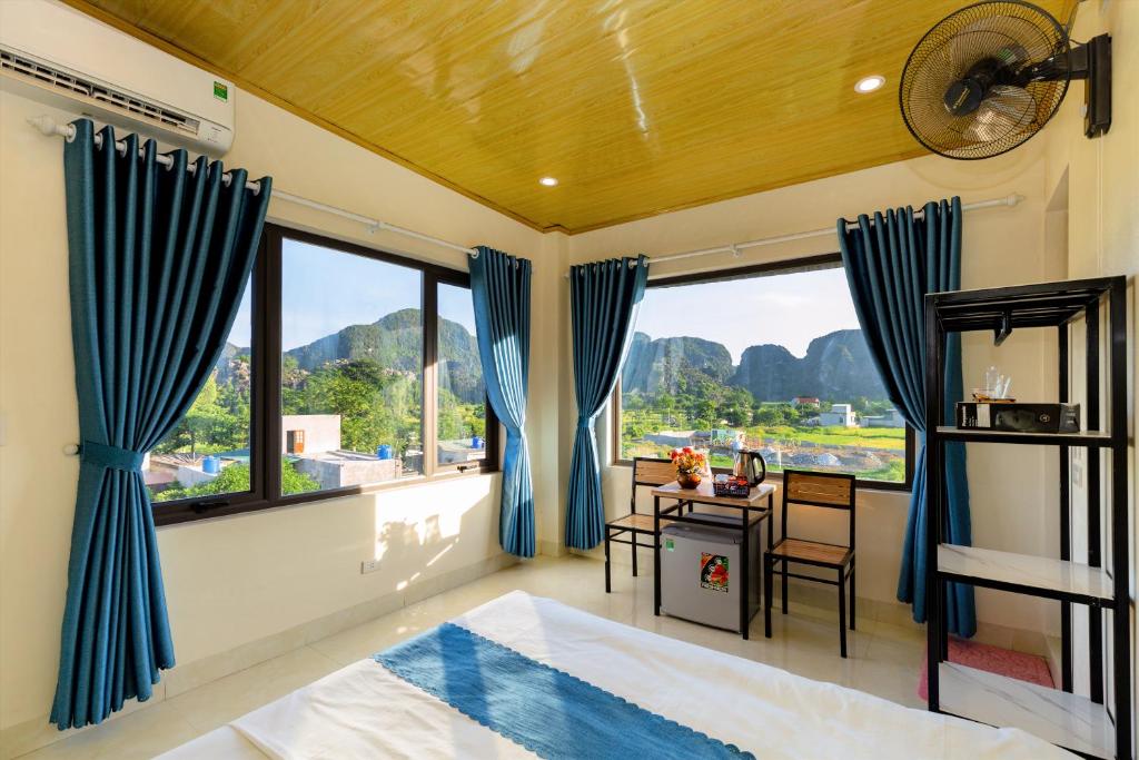 a bedroom with blue curtains and a desk and a bed at Cherry homestay in Ninh Binh