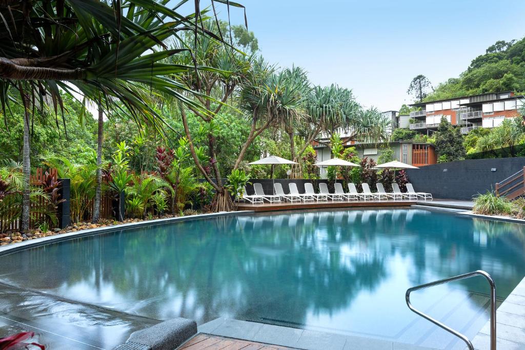 a large swimming pool with chairs and trees at Peppers Noosa Resort and Villas in Noosa Heads