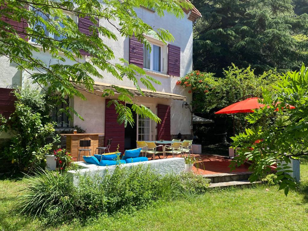 a house with a yard with chairs and an umbrella at Villa Riviera Chambres Privées in Amélie-les-Bains-Palalda