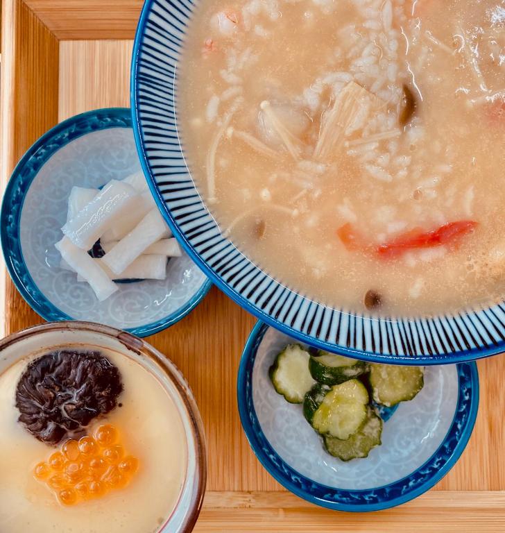 three bowls of soup and vegetables on a table at Shire Homestay in Luodong