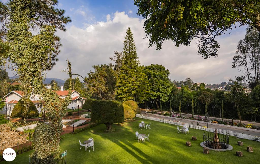 einen Garten mit weißen Tischen und Stühlen auf einer Wiese in der Unterkunft Savoy - IHCL SeleQtions in Udagamandalam