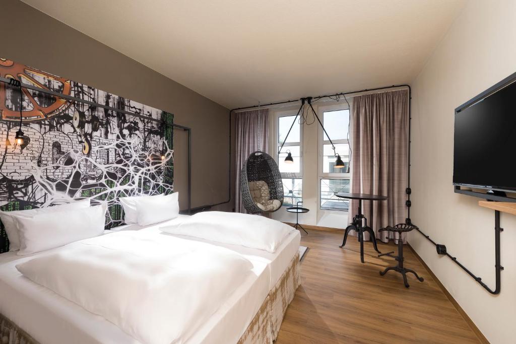 a bedroom with a large white bed and a tv at Seminaris Hotel Nürnberg in Nuremberg