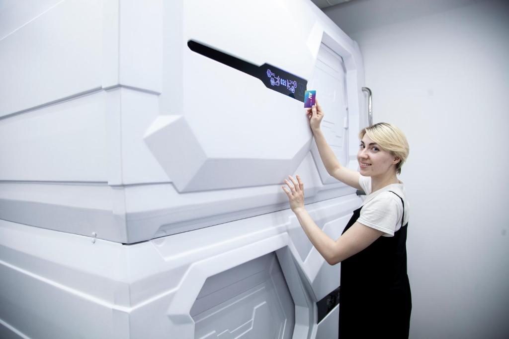 a woman is painting a wall with a remote control at AV-1 Capsule Hotel in Kyiv