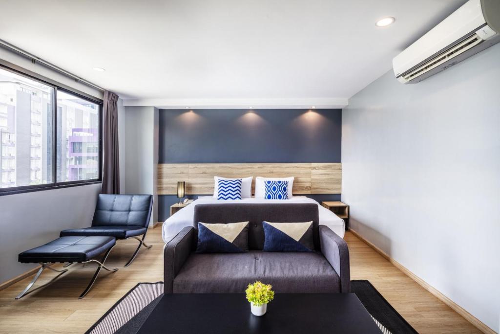 A furnished bedroom with a bed, sofa, coffee table and lounge chair.