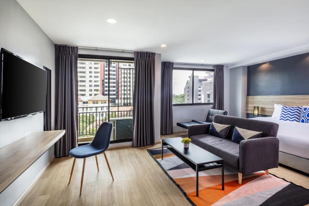 A spacious-looking room with a bed, sofa, desk, television and balcony doors.