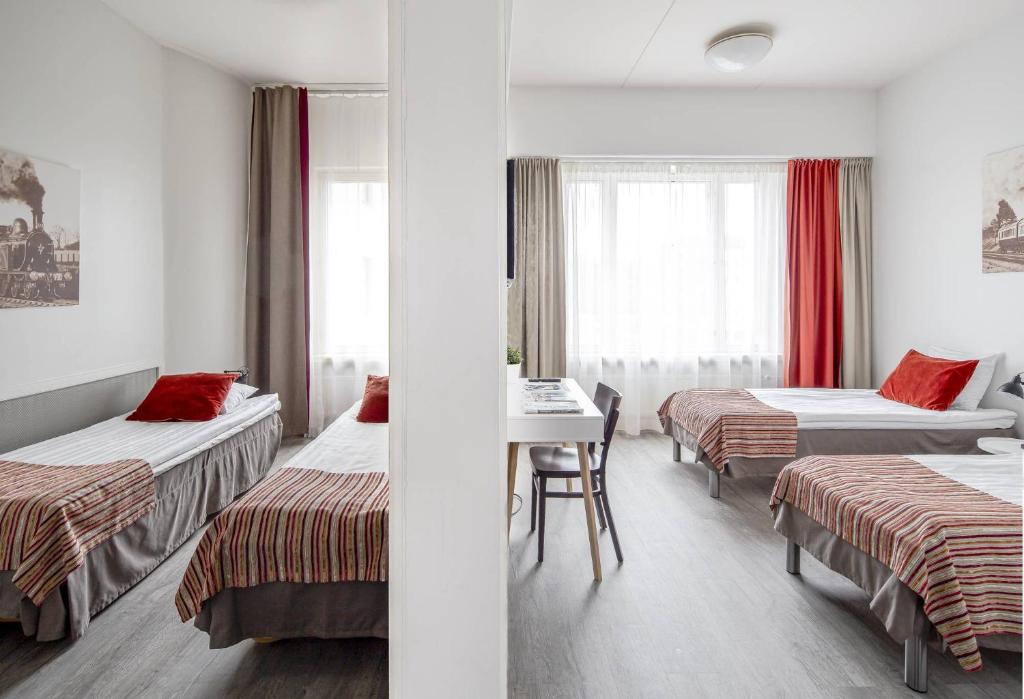 Habitación de hotel con 2 camas y mesa en Hotel Seurahuone Riihimäki en Riihimäki