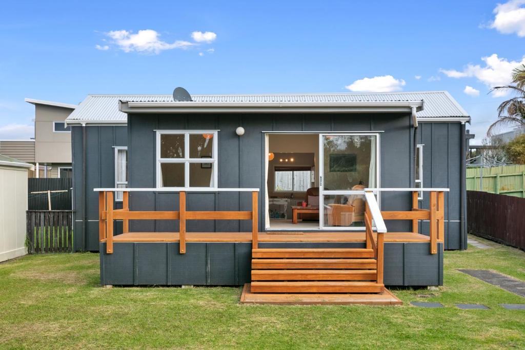 ein kleines blaues Haus mit einer Veranda und einer Terrasse in der Unterkunft Clara's Togs and Towels - Waihi - Bachcare NZ in Waihi Beach