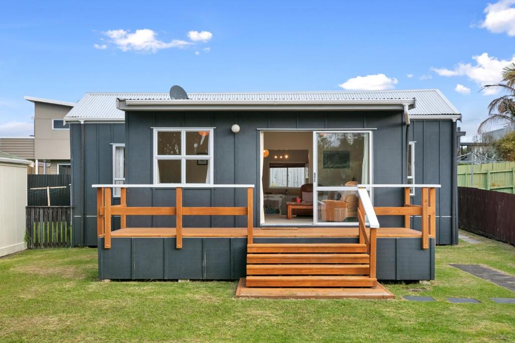 a blue tiny house with a porch and a deck at Clara's Togs and Towels - Waihi - Bachcare NZ in Waihi Beach