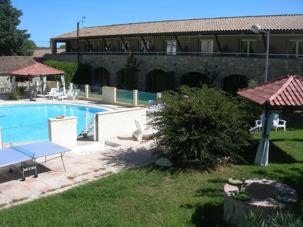 a pool in a yard with a building in the background at Hôtel de la Madeleine à Tornac in Tornac