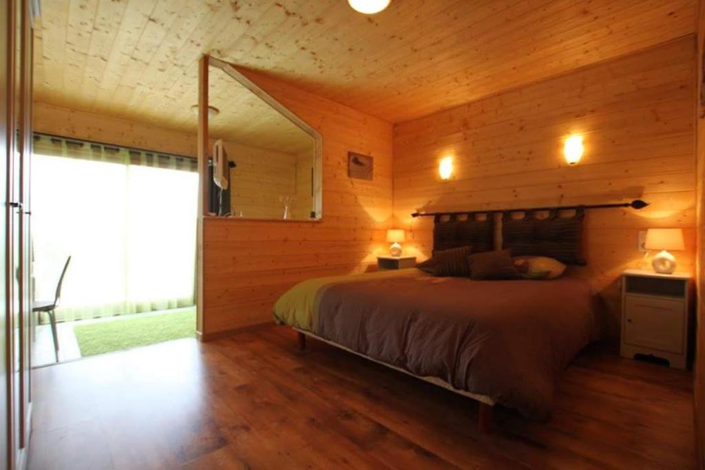 1 dormitorio con 1 cama en una habitación de madera en Les sentiers du lac, en Sorèze