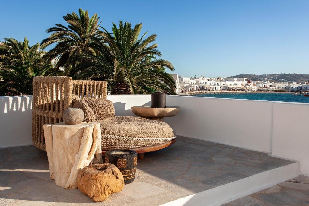 a rattan chair on a balcony with a view of the water at Island Mykonos Suites in Mýkonos City