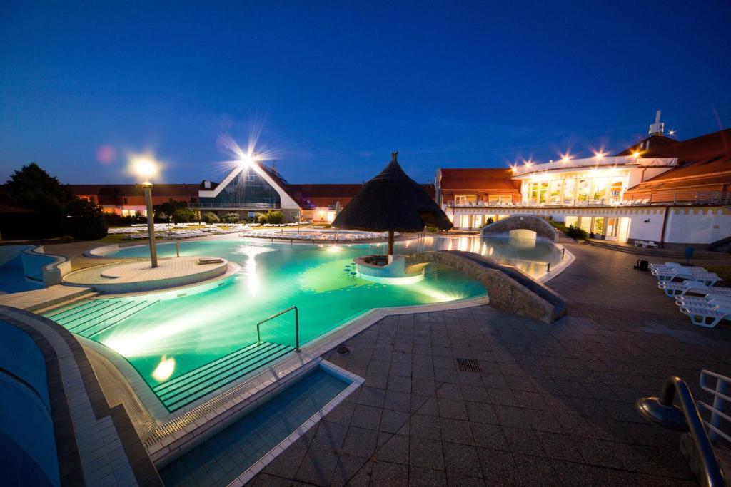 una gran piscina por la noche con luces en Kehida Termál Resort & Spa, en Kehidakustány
