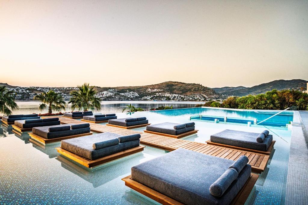 a swimming pool with chaise lounges on the water at Cape Bodrum Luxury Hotel & Beach in Gundogan