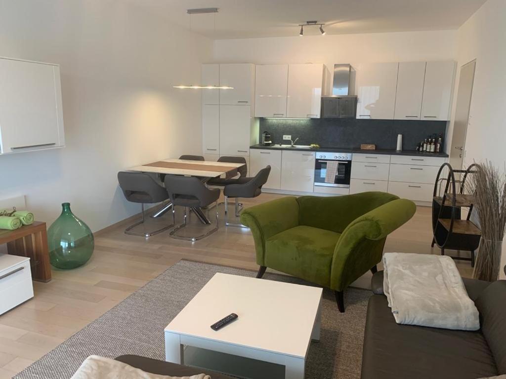 ein Wohnzimmer mit einem grünen Sofa und einer Küche in der Unterkunft Apartment am Weinberg in Ehrenhausen