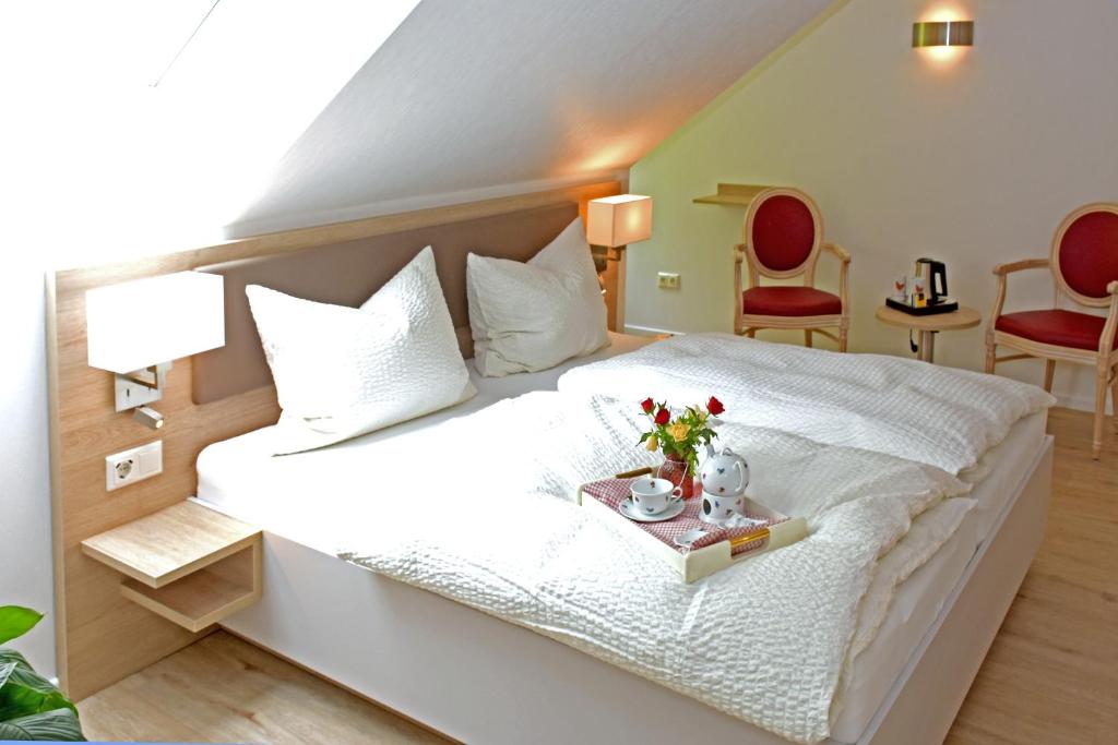 a bedroom with a large white bed with a tray of flowers on it at Der Eichenhof in Hellwege