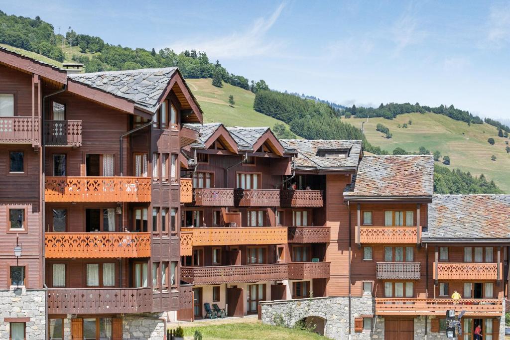 a large apartment building with a hill in the background at Quartier La Forêt - maeva Home in Valmorel