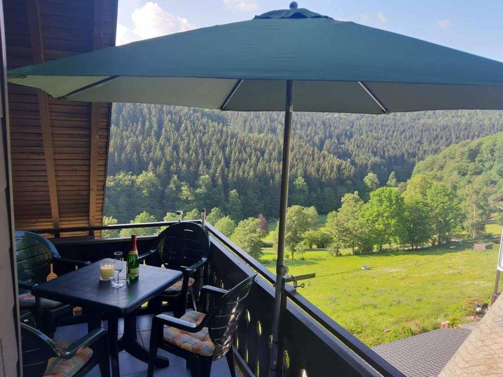 Ferienwohnung Nordenau في شمالنبرغ: مظلة زرقاء على شرفة مع طاولة وكراسي