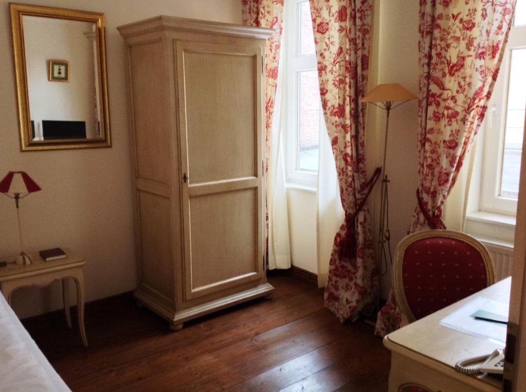 a room with a cabinet and two windows at Hotel Adler in Rudolstadt