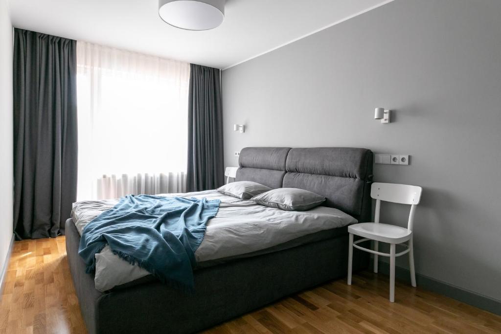 a bedroom with a bed with a chair and a window at Brand New, Family-friendly with a great location - Moon Apartment in Ventspils