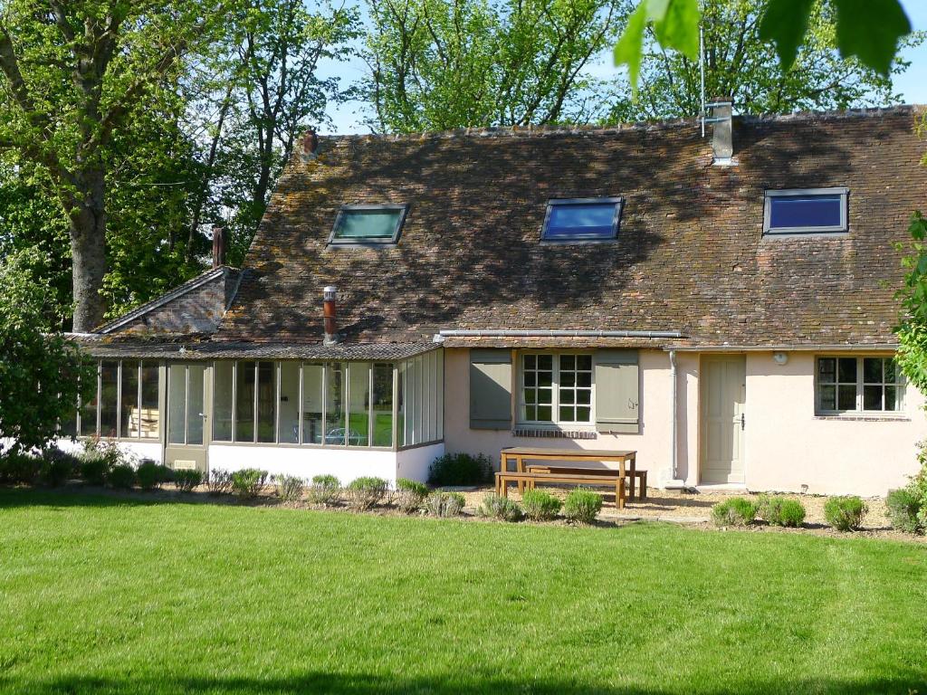 ein weißes Haus mit einer Bank im Hof in der Unterkunft Gite du moulin de Blanville in Saint-Luperce