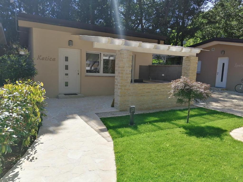 a house with a patio and a grass yard at Holiday Park Mimoza in Bašanija