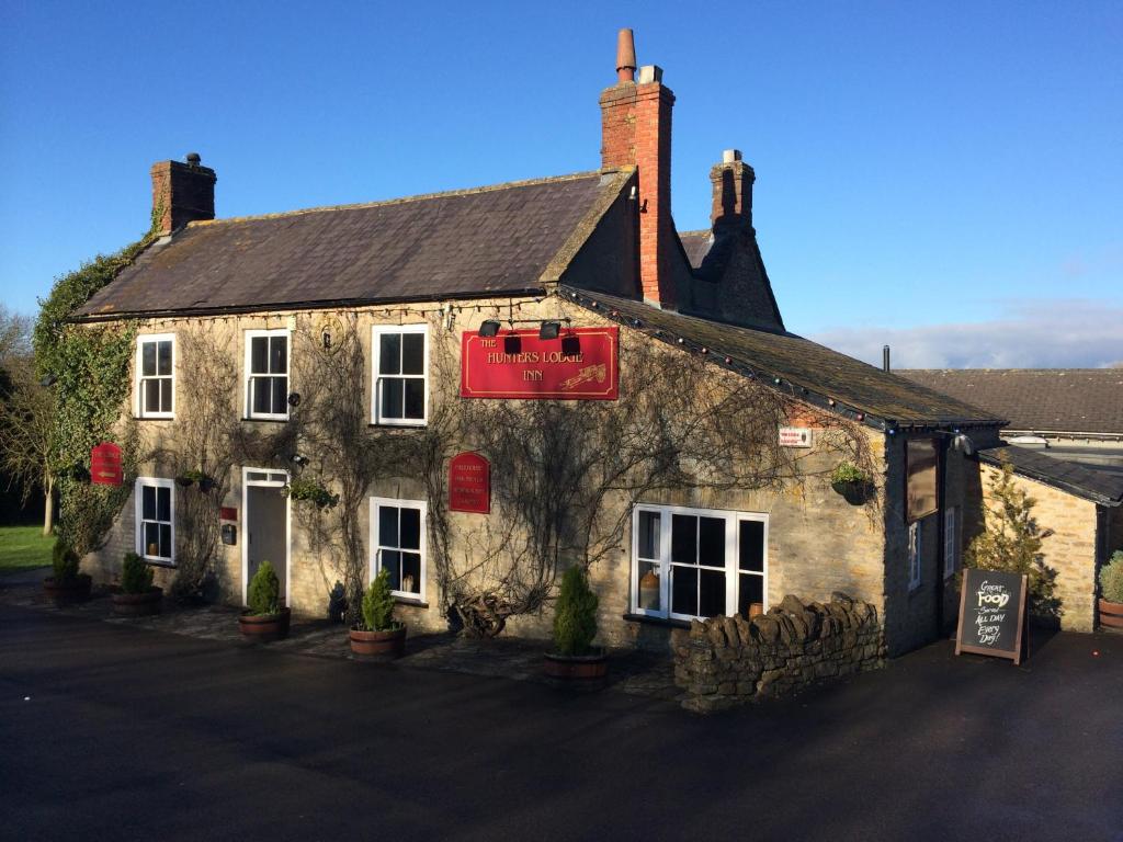 an old stone building with a red sign on it at Hunters Lodge Inn in Wincanton