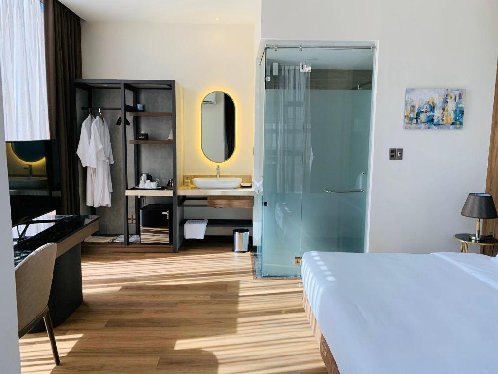 a bedroom with a bed and a bathroom with a sink at Hadiva Boutique Hotel in Danang
