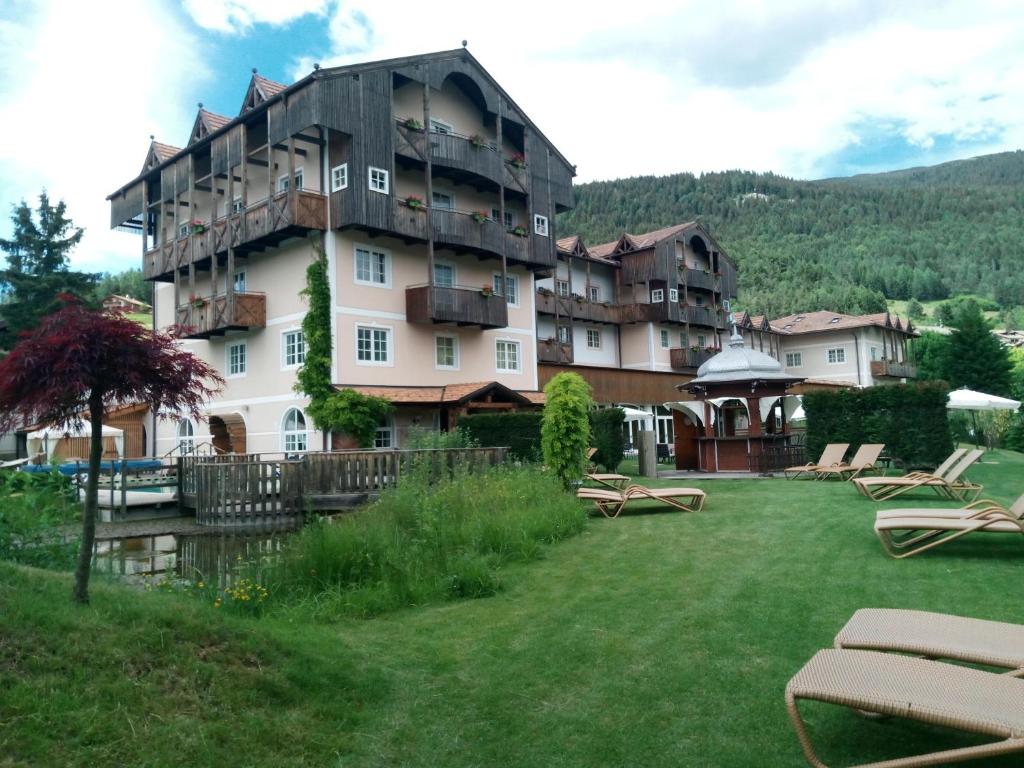 a large apartment building with a yard with chairs at Alpen Hotel Eghel in Folgaria