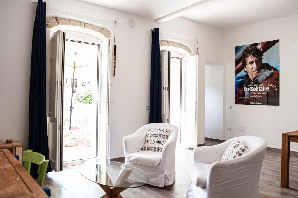salon z 2 białymi krzesłami i szklanym stołem w obiekcie la Casa Amaranto w mieście SantʼAntìoco