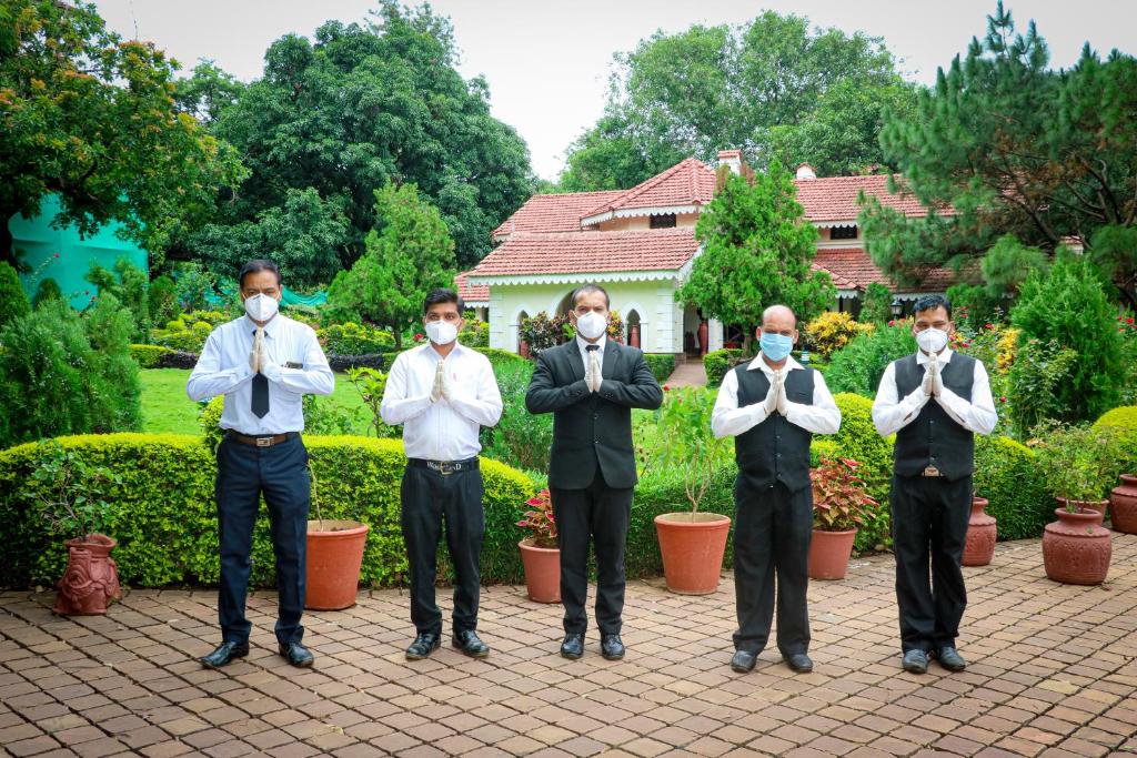 a group of men wearing masks standing in front of a garden at WelcomHeritage Golf View in Pachmarhī