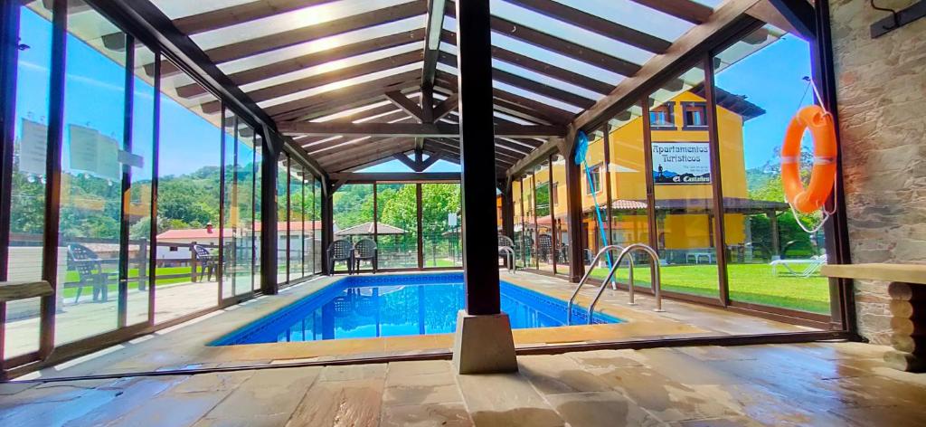 a swimming pool inside of a building with windows at Apartamentos El Castañeu in Corao