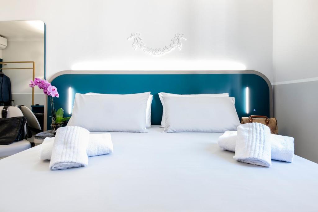 Cama blanca con almohadas blancas y cabecero azul en Hotel Grifo en Roma