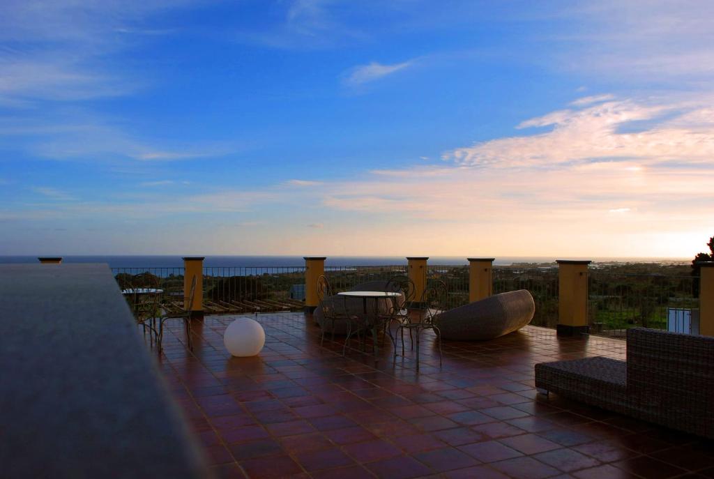 a patio with a view of the ocean at sunset at Hotel Resort La Rosa Dei Venti in Portopalo