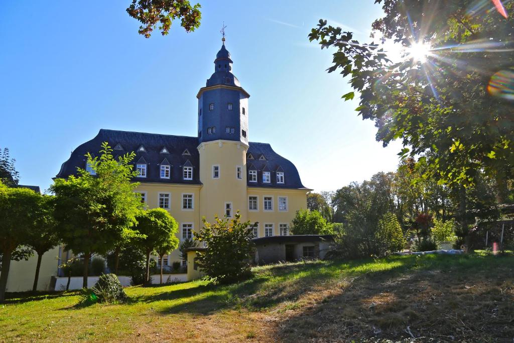 un edificio con una torre de reloj en la cima de una colina en Schlosshotel Domäne Walberberg en Bornheim