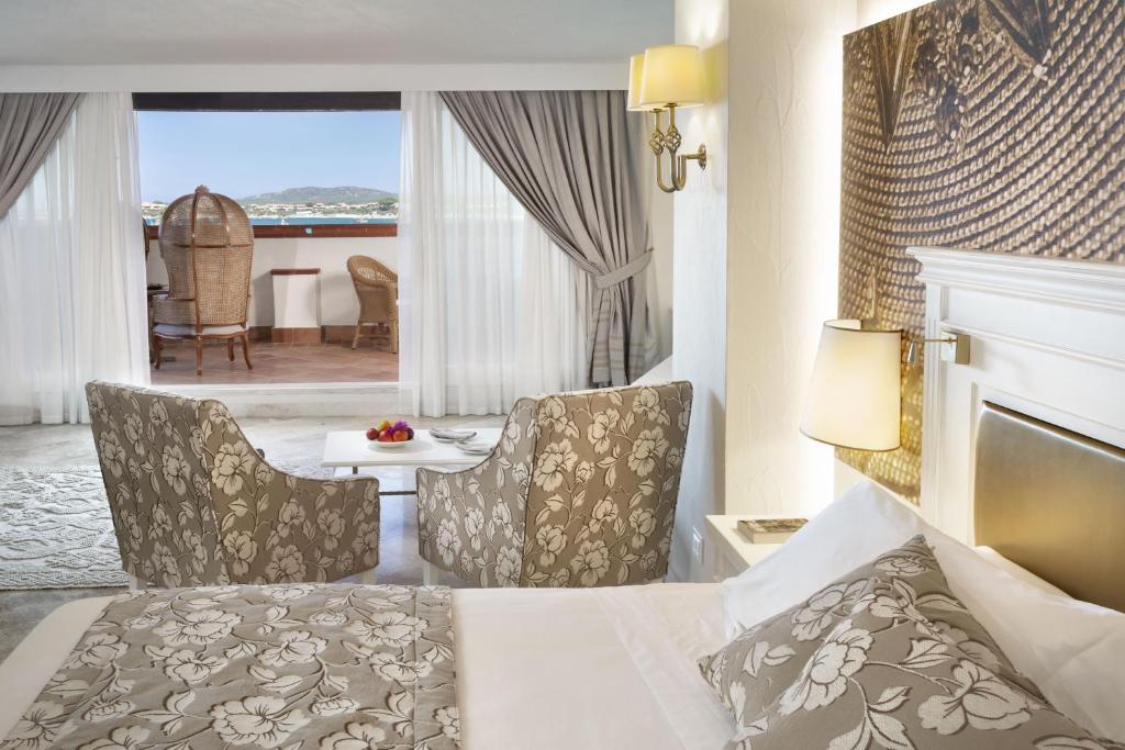 a hotel room with a bed and chairs and a table at Hotel Abi d'Oru in Porto Rotondo