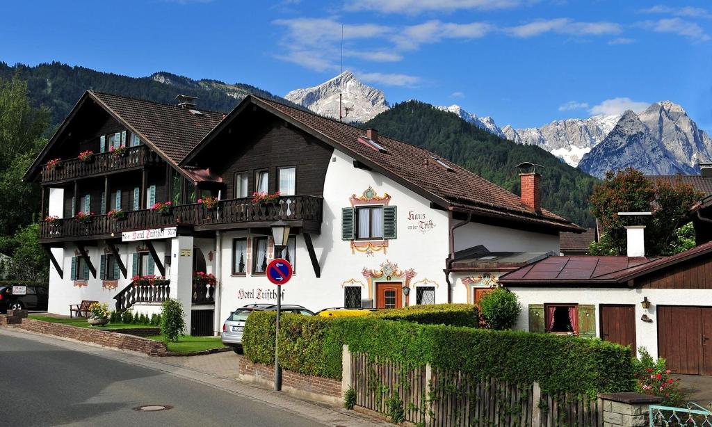 a large white house with mountains in the background at Weidegg - Hotel Garni in Garmisch-Partenkirchen