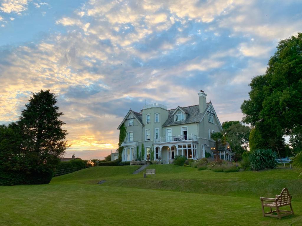 a large white house sitting on a lush green field at Pencubitt House in Liskeard