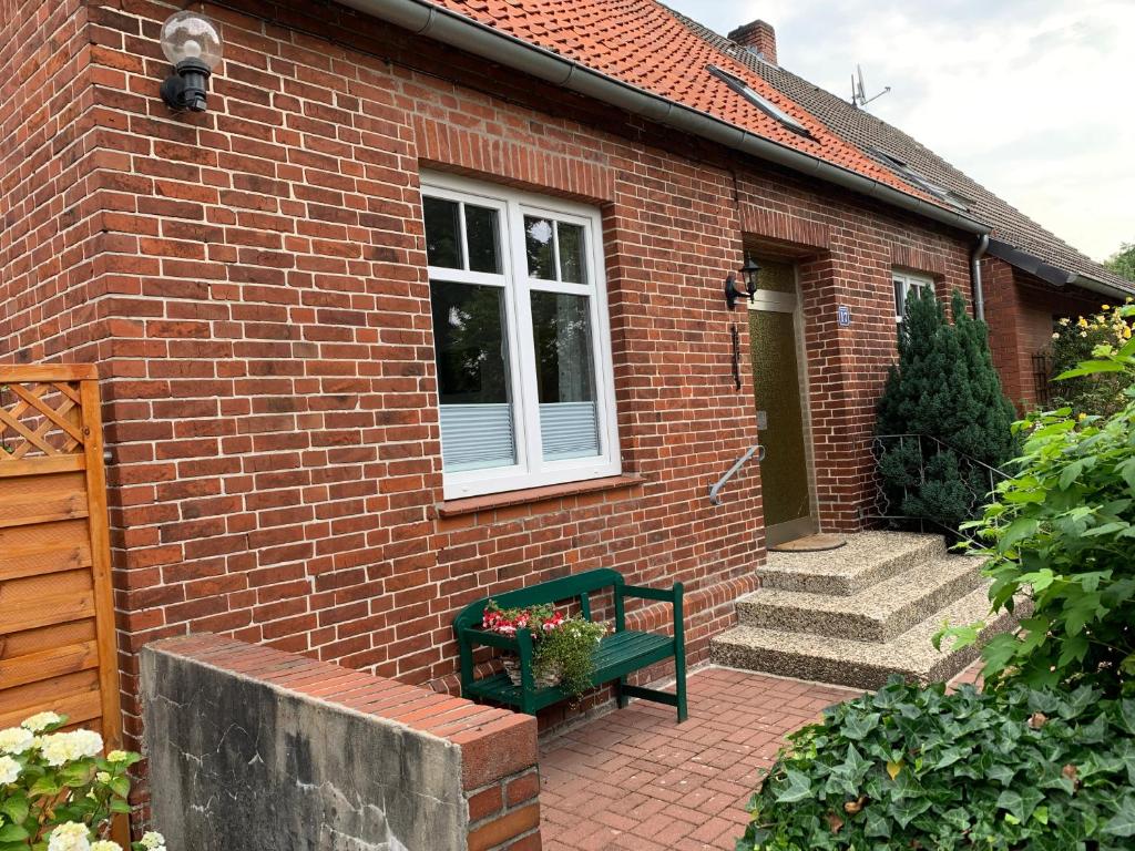 a green bench sitting outside of a brick house at Ferienhaus Fegebank in Nienhagen in Nienhagen