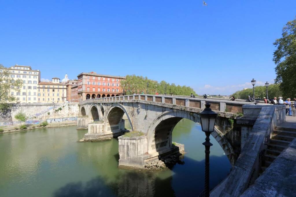 eine Steinbrücke über einen Fluss in einer Stadt in der Unterkunft Welcome to Trastevere in Rom