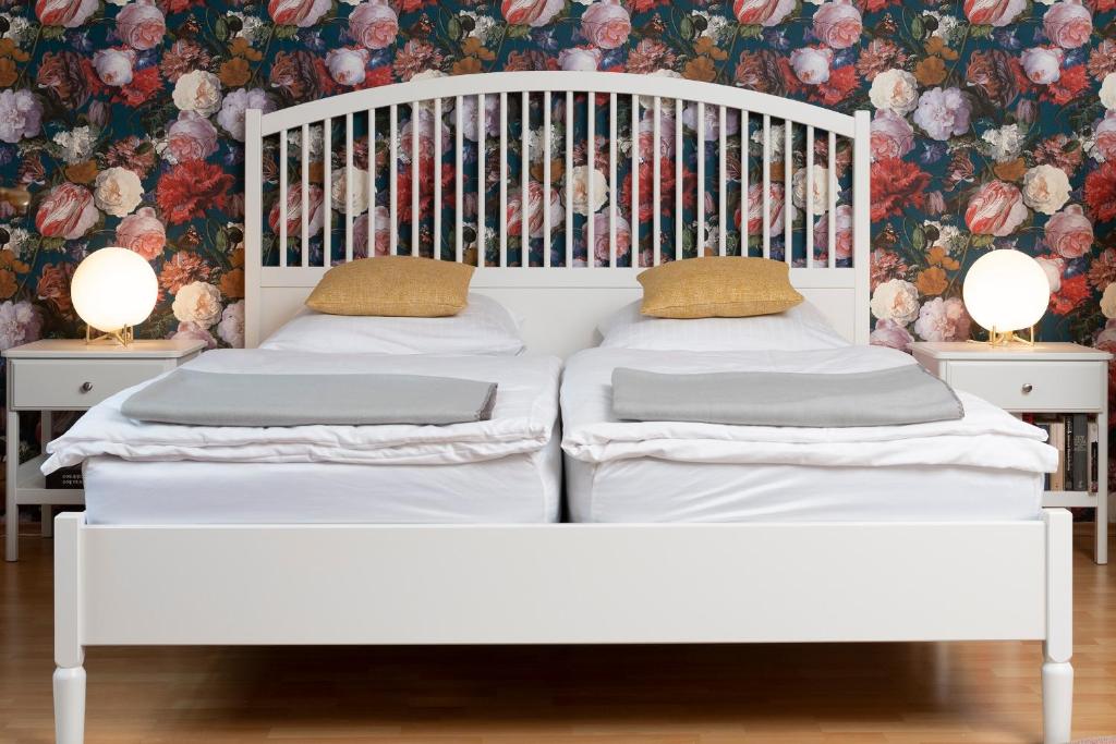 two white beds in a room with a floral wallpaper at Zu Hause im schönen Tirol in Kirchbichl